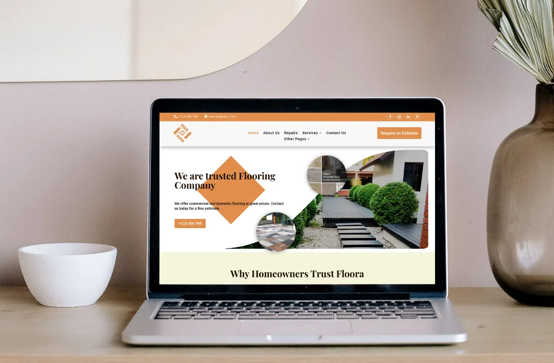 "A professional laptop mockup displaying the 'Trusted Flooring Company' website template. The screen features a warm orange, tan, and white color palette, high-quality imagery of modern wood flooring and exterior landscaping, and the bold headline 'We are trusted Flooring Company.' It highlights a prominent 'Request an Estimate' call-to-action button and a structured 'Why Homeowners Trust Floors' section. The laptop is set on a minimalist wooden desk."