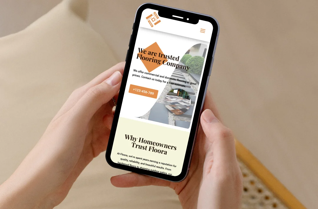 "A close-up of a person holding a smartphone displaying the mobile-responsive 'Trusted Flooring Company' website. The screen shows a clean, vertically-optimized layout with a prominent orange 'Call Today' button, the company logo, and an authoritative section titled 'Why Homeowners Trust Floors.' The design emphasizes ease of use for customers looking to book flooring services on the go."