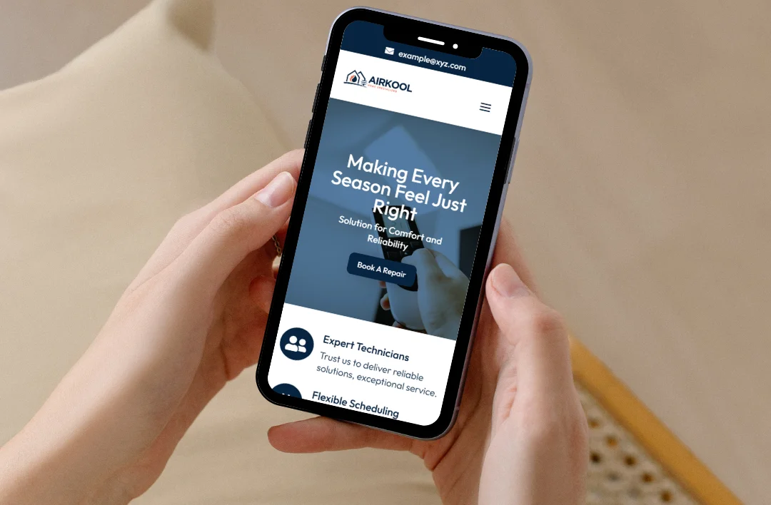 A person holding a smartphone displaying a mobile-optimized HVAC website with the headline 'Making Every Season Feel Just Right' and a 'Book a Repair' call-to-action button.