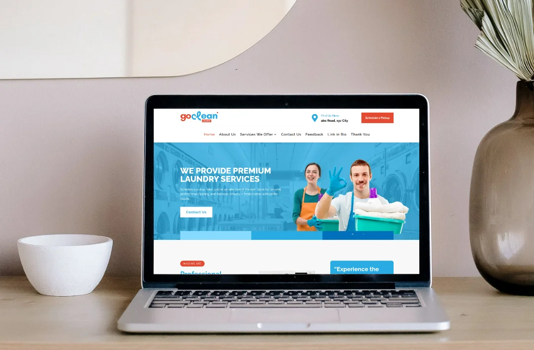 "A professional laptop mockup displaying the 'GoClean' laundry service website template. The screen features a bright and airy sky-blue and white theme, high-quality imagery of a smiling service team, and the bold headline 'We Provide Premium Laundry Services.' It highlights a prominent 'Schedule a Pickup' call-to-action button and clear navigation. The laptop is set on a minimalist wooden desk in a bright, modern room."