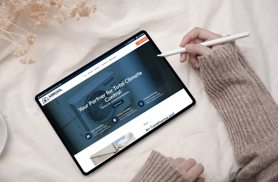 A person using a stylus on a tablet displaying a professional HVAC website for 'Air Kool' with the headline 'Your Partner for Total Climate Control' in a clean, modern workspace.