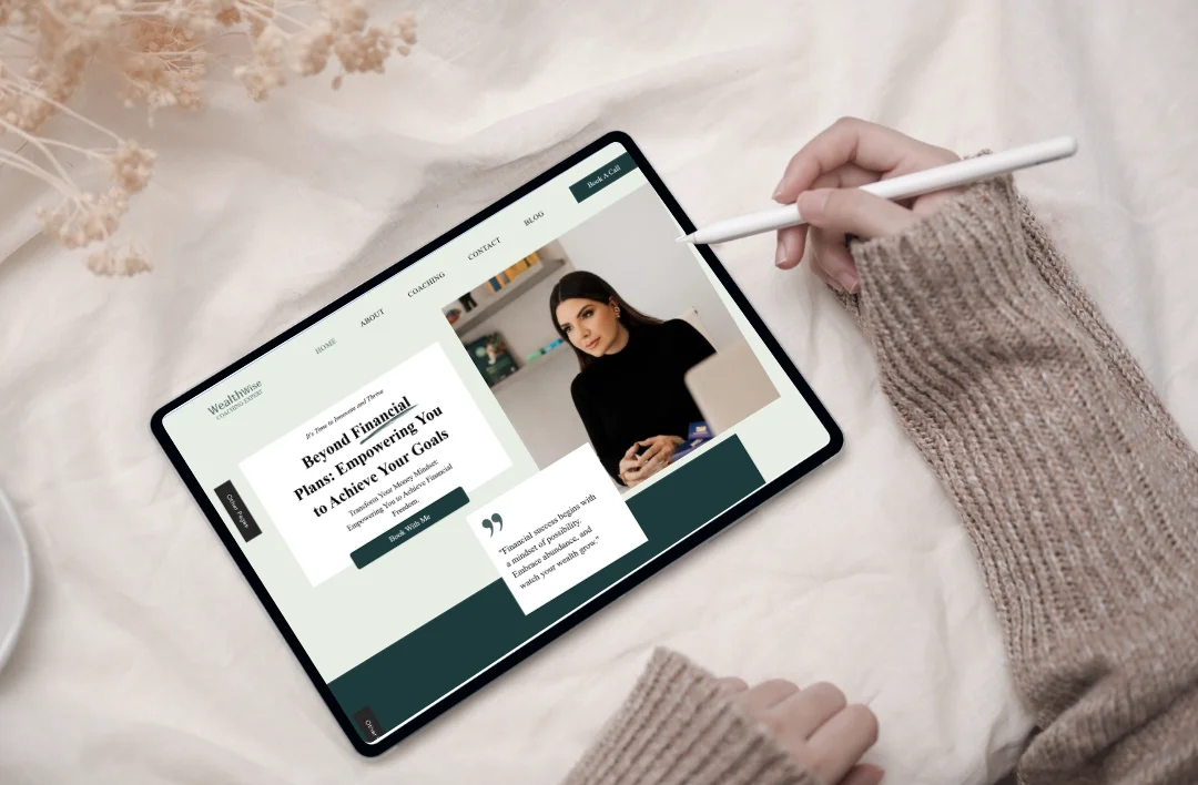 Top-down lifestyle mockup of a 'Financial Coaching' Wix website template displayed on a tablet with a stylus. The professional design features a dark green and white theme, a sophisticated coach portrait, and clean typography. Set against a soft aesthetic background with dried flowers.